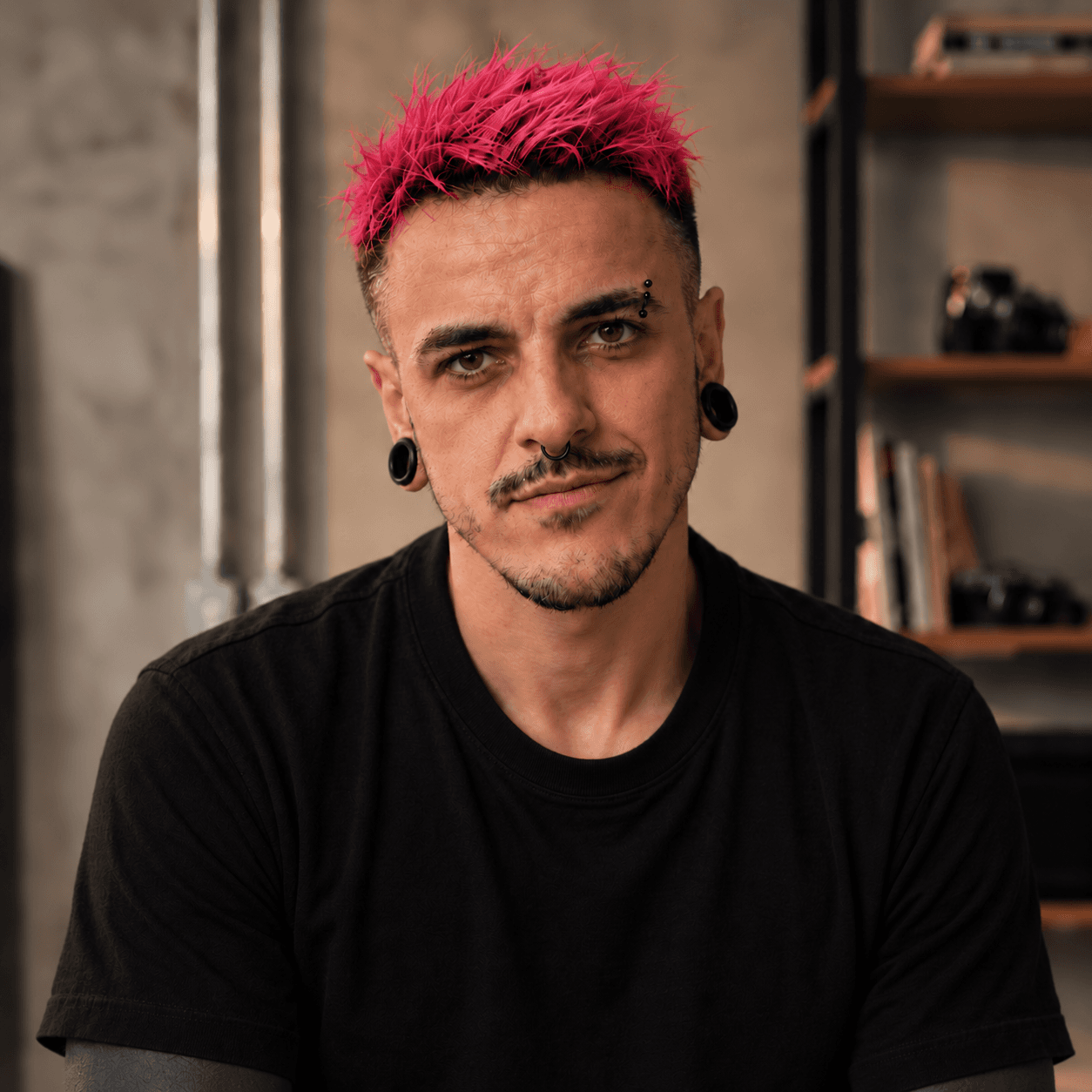 MS MAGENTA, com cabelo rosa e camiseta preta, em seu estúdio.